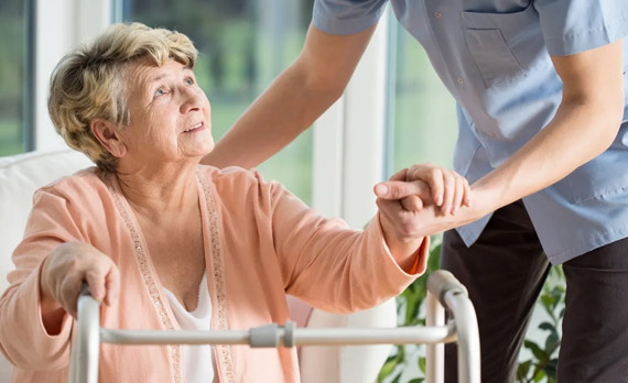 A woman holding the hand of another person in a wheelchair.